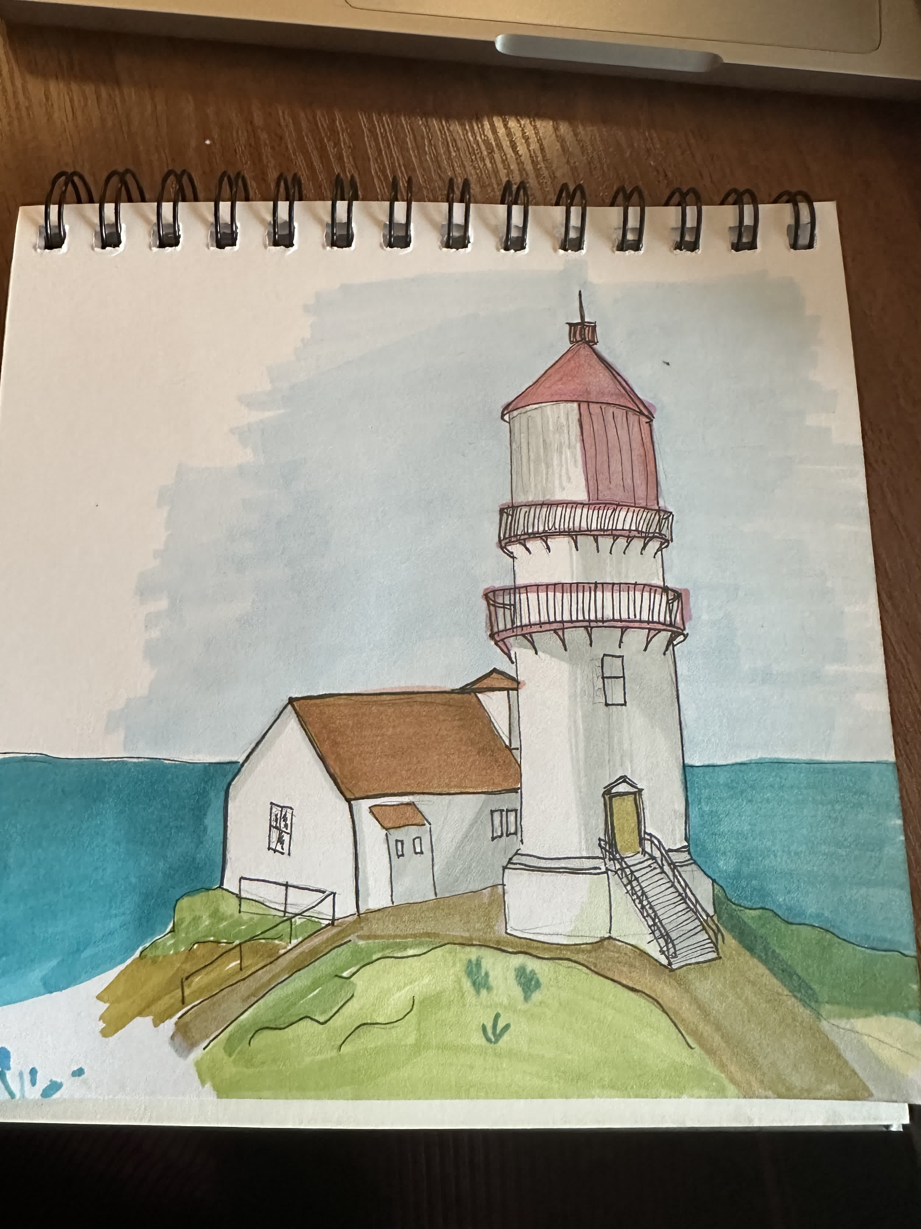 White lighthouse with red railings and a red roof beside a small white house on a grassy cliff above the sea.