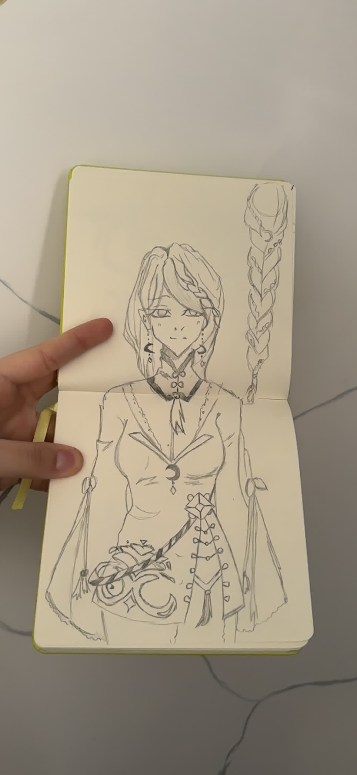 Pencil sketch of a girl with a long braid, crescent moon pendant and buttoned dress, with a braid study beside her.