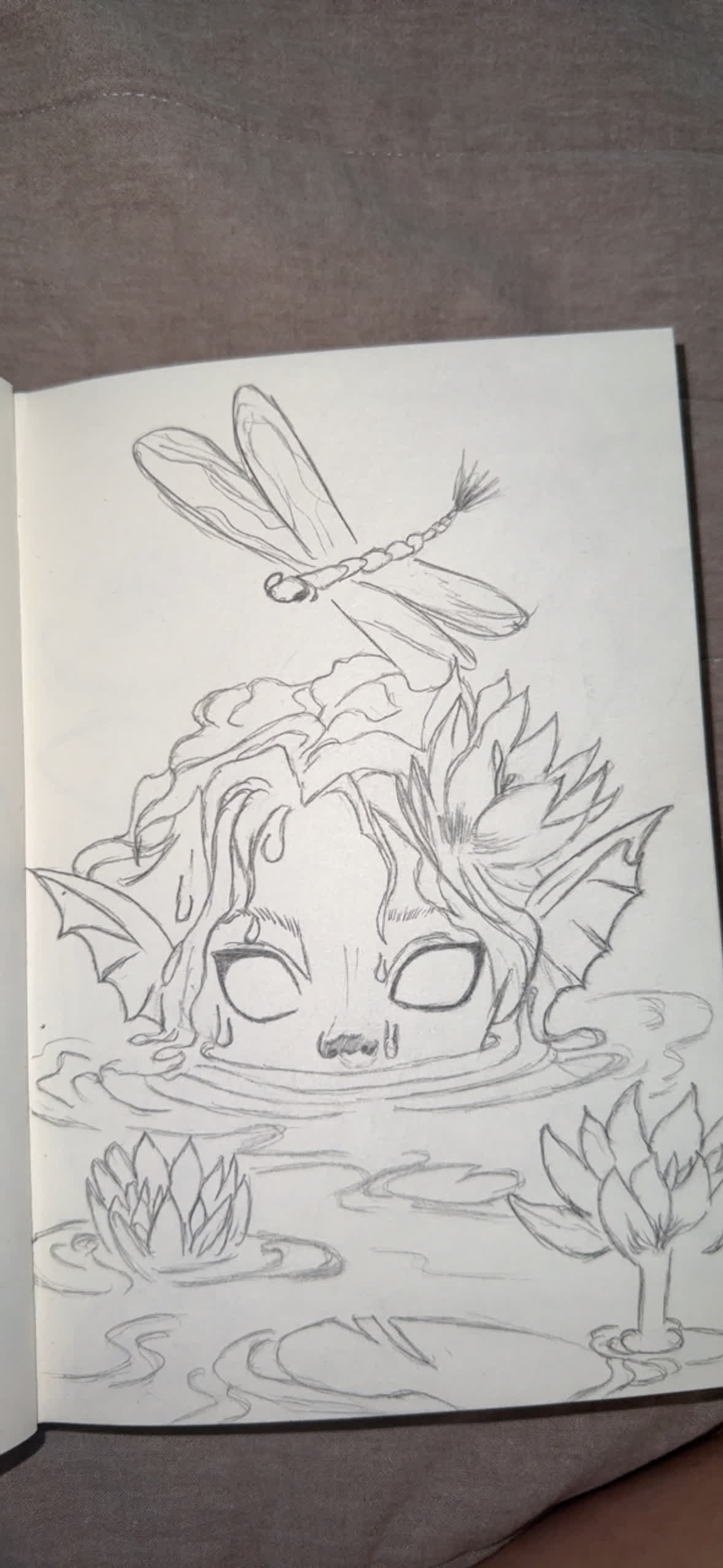 Sketch of a water spirit with closed eyes half sunk in a pond, a dragonfly above her head and lotus flowers around.
